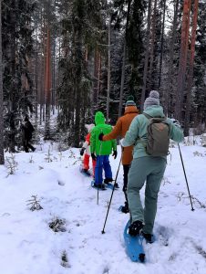 een familie gaat met sneeuwschoenen het bos in